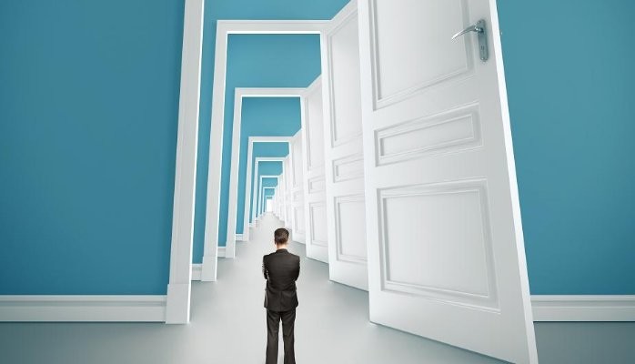A businessman standing in front of multiple doors